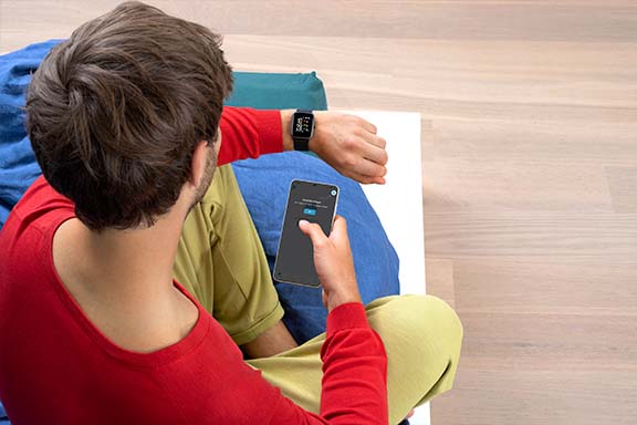 Person mit Smartwatch und Smartphone in der Hand.